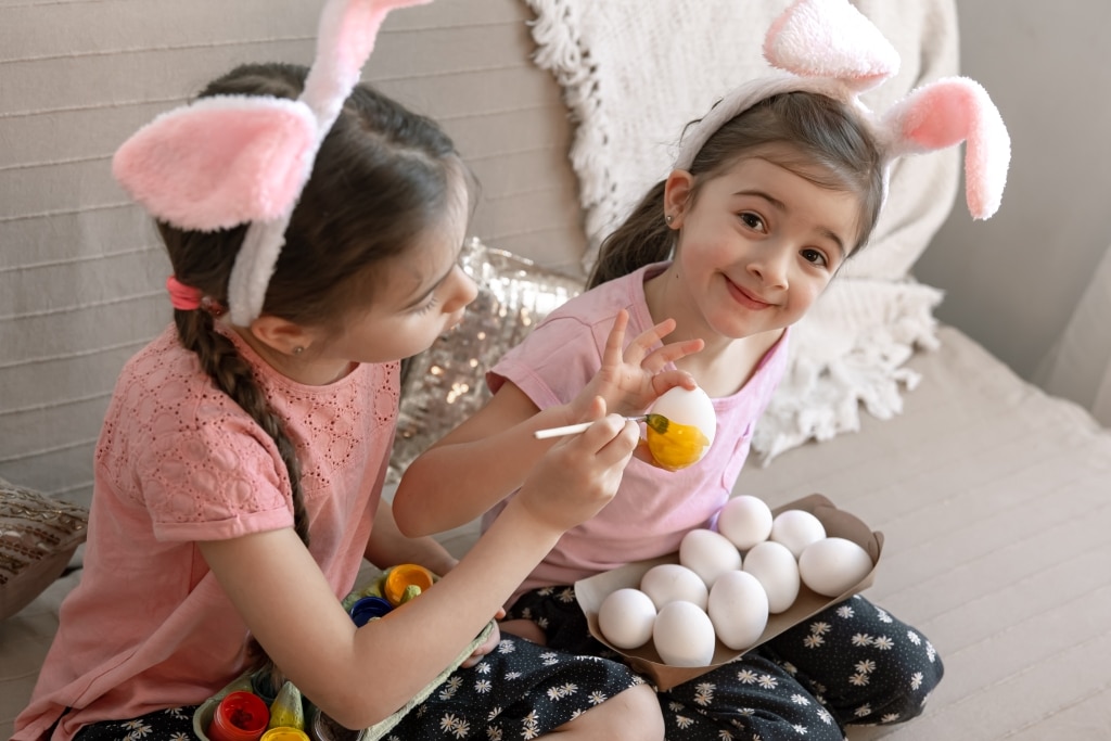 Soeurs fétant pâques faisant une activité créative dessinant sur des oeufs